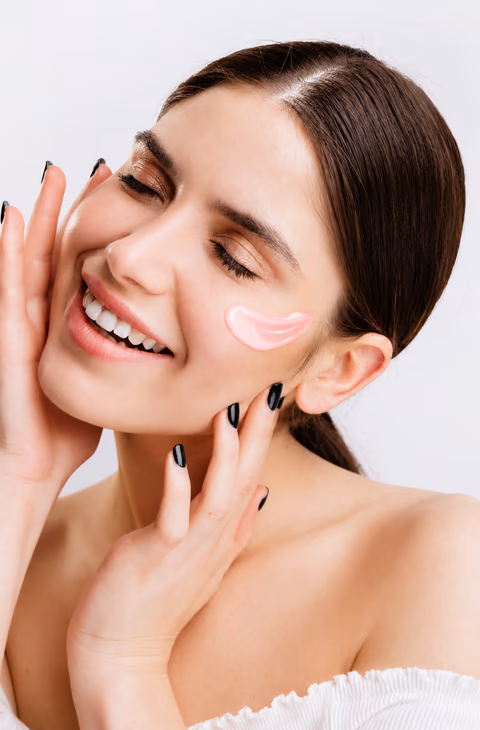 A woman smiling with a dab of pink gel on her cheek